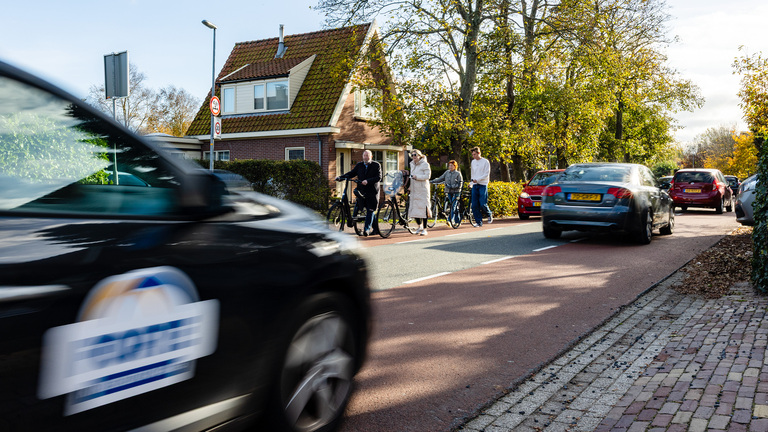 Het groepje raadsleden en de vrouwen van de bewonersvereniging gaan met de fiets aan de hand over de fietsstrook van de Herenweg.