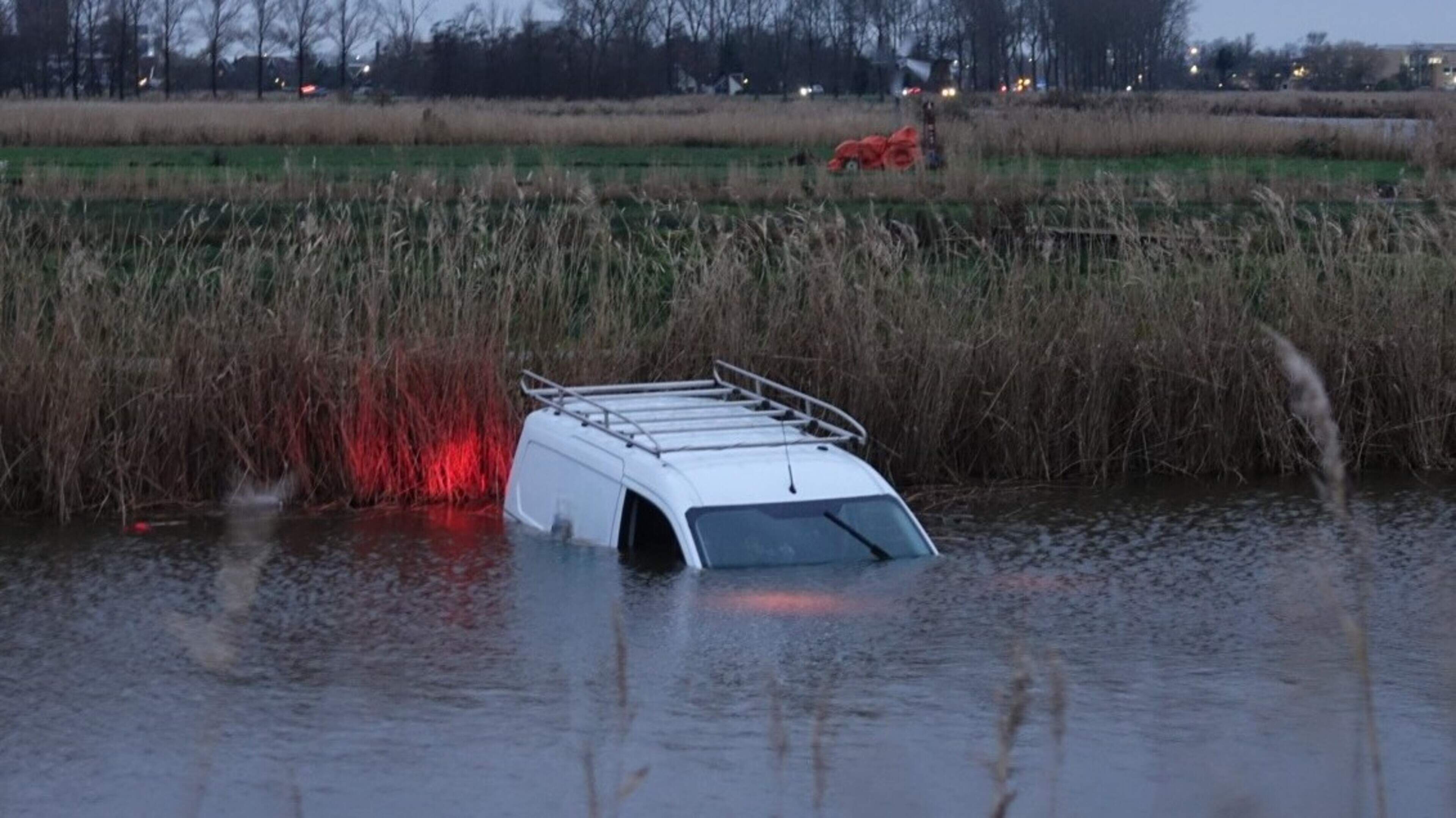 Bedrijfsbusje te water langs dijk in Wijdewormer, bestuurder naar ziekenhuis