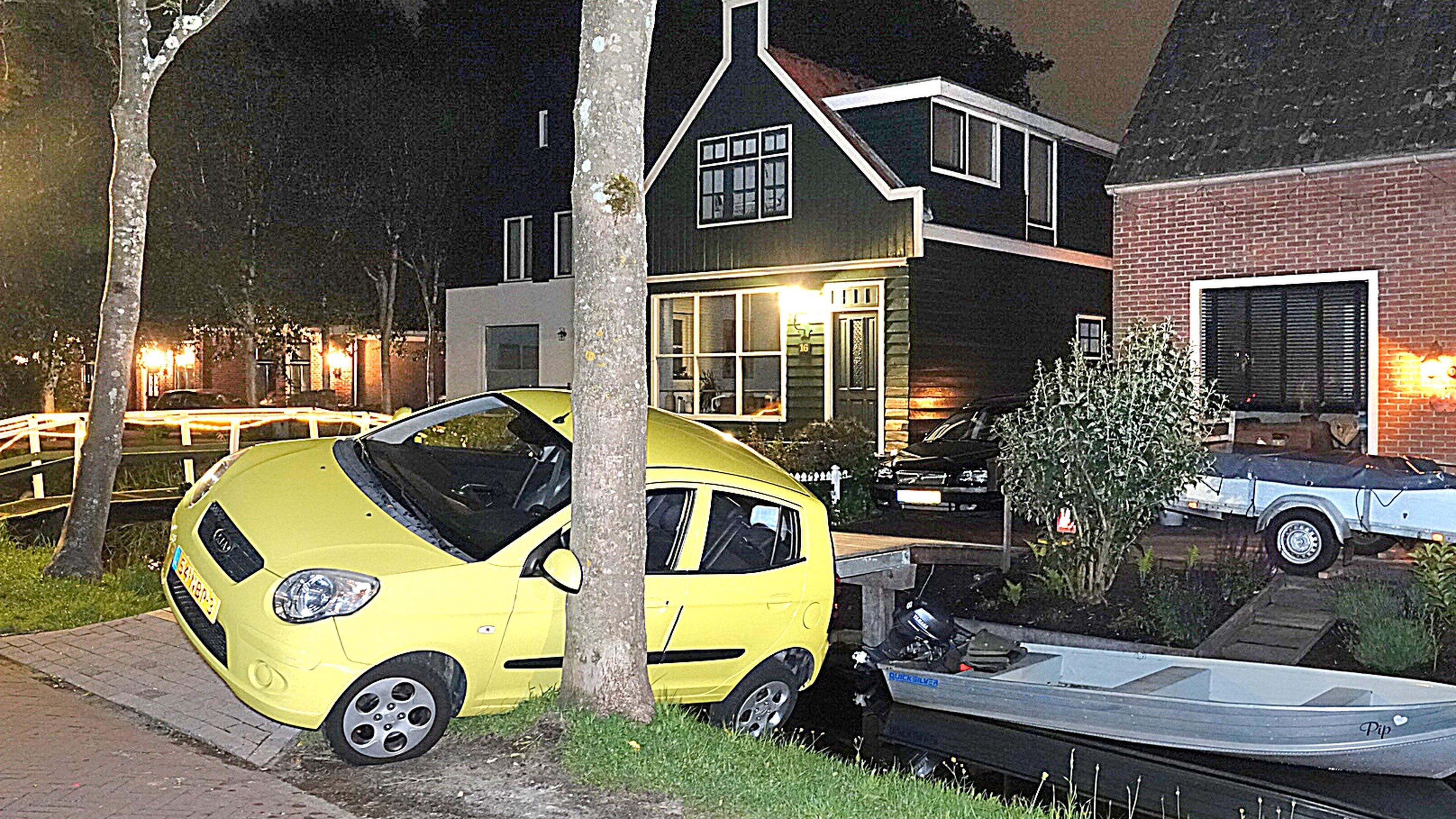 Auto bungelt van brugje en rust tegen boom in Jisp